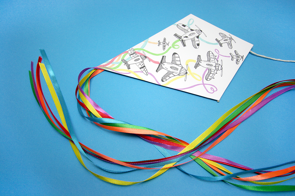 Wykonany papierowy latawiec dla dziecka z kolorowymi tasiemkami