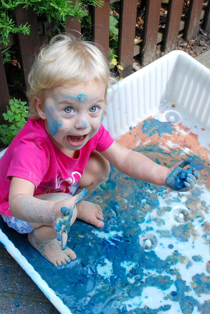 Dziecko bawiące się w misce z niebieską cieczą nienewtonowską.