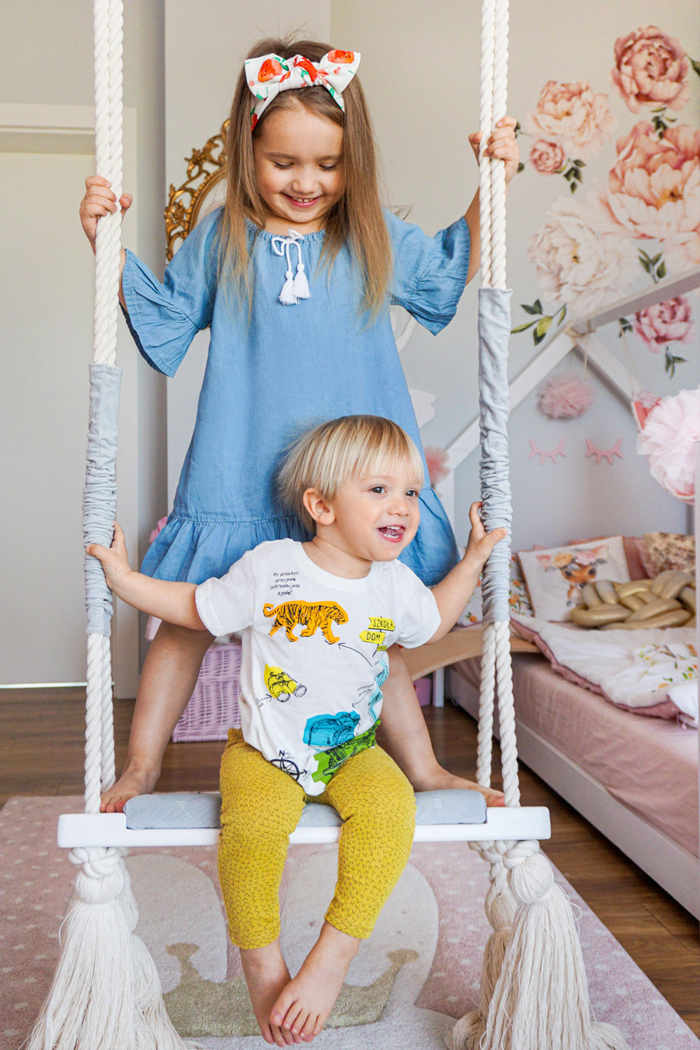 Zabawy na urodziny w domu Dwie dziewczynki uprawiające gimnastykę w swoim kolorowym pokoju. Mama i córka świętujące urodziny. Dwoje dzieci malujących na szybie.|Dwie dziewczynki w koszulkach w rowerowy wzór i w papierowych okularach.